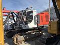 A 2018 Sandvik Ranger DX800 drill rig with a white and gray body mounted on tracks and equipped with a red power unit and various attachments