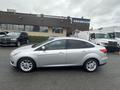 A silver 2018 Ford Focus is parked with a side view showcasing its sleek design and alloy wheels