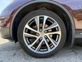 A close-up of a shiny alloy wheel with a multi-spoke design mounted on a 2017 Infiniti QX50