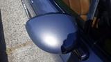 A close-up view of the side mirror of a 2007 Mazda Miata with a shiny blue paint finish and a sleek design
