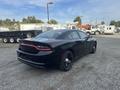 A black 2015 Dodge Charger parked with a sleek design featuring a distinctive rear light bar and black wheels