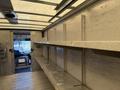 Interior view of a 2012 Ford Econoline with empty shelves along the walls and a driver's seat visible at the front