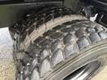 Close-up of a heavy-duty tire with deep treads mounted on a 2015 Freightliner M2 truck showing wear and dirt on the surface