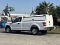 A white 2019 Ford F-150 with a truck bed cover parked at an angle showing its side view and wheels