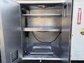Interior of a metal storage compartment with two shelves and a sliding drawer at the bottom inside a vehicle