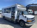 A white 2020 Chevrolet Express bus with large windows and a streamlined design parked and facing slightly to the left