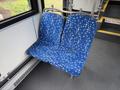 Two blue patterned bus seats with a white abstract design inside a bus interior