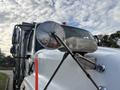 Close-up of a 2013 Freightliner 114SD truck featuring a side mirror and light with a shiny white surface and chrome accents