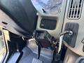 A close-up view of the steering column of a 2011 International 4300 showing buttons a gear stick and a mounted device holder