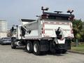 A 2013 International WorkStar truck with a white body, equipped with a rear-mounted dump bed and various lights on the top.