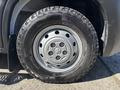 A close-up view of a gray steel wheel with a black tire featuring aggressive tread patterns designed for enhanced traction and durability