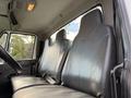Interior view of a 2011 International 4300 showing two high-backed black leather seats with seatbelts and a steering wheel in the foreground