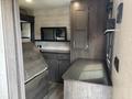 Interior of a 2021 Jayco Jay Flight featuring a brown wooden table and cabinets with a mirror positioned against a wall in a well-lit space