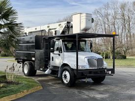 A white 2012 International DuraStar 4300 equipped with a bucket lift and a black utility bed parked on a street