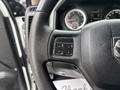 Close-up of the steering wheel of a 2013 RAM 1500 featuring control buttons for vehicle settings and a textured grip