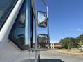 A 2012 Ford E-450 with large side mirrors seen from a low angle emphasizing the vehicle's profile and reflective surfaces