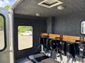 Interior of a 1994 Volvo FE 42 featuring a row of black seating with safety restraints attached to a wooden backing and a ceiling light fixture