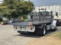 A 2020 Peterbilt 330 flatbed truck parked with a black flatbed and orange rollers at the rear