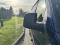 A blue 2013 Ford E-350 Super Duty van with a focus on the side mirror reflecting light