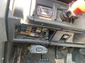 Dashboard of a 1996 GMC Top Kick showing various buttons switches and a fuse panel with colored fuses and a small digital display for monitoring