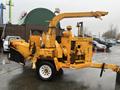 A yellow 1993 Bandit 200 wood chipper with a large feeding chute and multiple controls mounted on a trailer with a wheel assembly