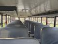 Interior view of a 2013 International 4300 school bus with rows of gray seats and emergency exit signs visible along the windows