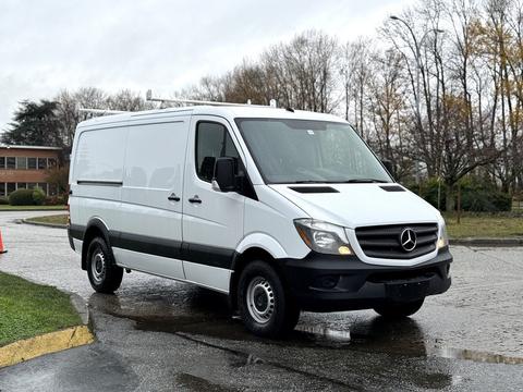 A 2017 Mercedes-Benz Sprinter van with a white exterior and black accents parked on a wet surface