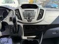 Interior dashboard of a 2018 Ford Transit featuring a control panel with buttons for audio and climate control along with gear shifter and cup holders