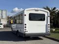 A white 2017 Chevrolet Express bus featuring large windows and a rear exhaust pipe, parked and facing away from the viewer