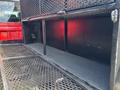 A 2013 RAM 2500 truck bed with a metal mesh divider and storage compartments on either side