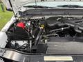 A 2012 Ford F-550 engine compartment showing the battery hoses and engine components with visible cables and a dipstick