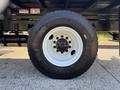 A close-up view of a white rim with a black tire mounted on a 2019 Freightliner M2 106 showing the wheel design and tread pattern