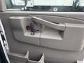 Interior door panel of a 2022 GMC Savana featuring a door handle power window control and storage compartments