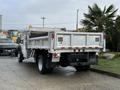 A 2012 Ford F-550 with a silver dump bed and a flatbed design parked in a driveway