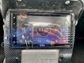 A close-up of a touchscreen car stereo displaying radio information with a blue circular graphic and various control options