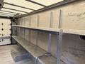 Interior of a 2012 Ford Econoline featuring metallic shelves along the walls and a flat floor space