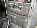The interior side door of a 2021 Chevrolet Express featuring a handle a lock button and storage compartments for drinks and small items