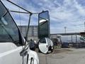 A 2015 Ford F-750 with a prominent side mirror and a small circular mirror attached to it reflecting the truck's body
