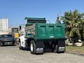 A green 2015 Peterbilt 337 dump truck with an open bed and black markings on the rear mud flaps