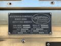 A metal plaque with engraved text detailing specifications and information for the Watrous Company, including model, serial number, pump capacity, and pressure ratings