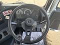 The interior of a 2012 Autocar Xpert featuring a black steering wheel with controls and gauges visible on the dashboard