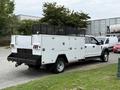 A 2020 Ford F-550 truck with a white service body featuring multiple compartments and a black mesh utility rack on the bed