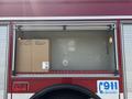 A 1999 Freightliner FL80 with storage compartments displaying several cardboard boxes and a 911 emergency sign on the side