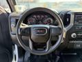 A 2022 GMC Sierra 1500 steering wheel with the GMC logo prominently displayed and dashboard controls visible behind it
