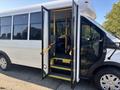 A 2017 Ford Transit-350 with open doors revealing steps and interior seating designed for passenger transport