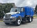 A blue and white 2013 International DuraStar 4300 street sweeper with a front-mounted broom and a large blue chassis on the rear