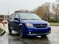 A blue 2020 Dodge Grand Caravan with a sleek design featuring black accents and modern headlights parked with raindrops on its surface