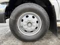 A close-up of a silver wheel and tire from a 2002 Ford Econoline displaying six lug nuts and a treaded tire pattern