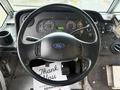 Steering wheel of a 2018 Ford E-450 with dashboard gauges and a black interior including a thank you note on the floor