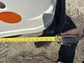 A person holding a tape measure extended along the side of a white 2012 Ford Econoline van